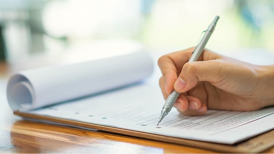 A person using a pen on a clipboard to complete a checklist for inventory storage.