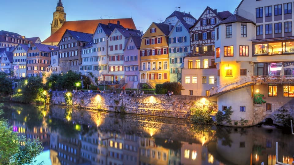 Colorful old town houses along a riverside at dusk with reflections in the water