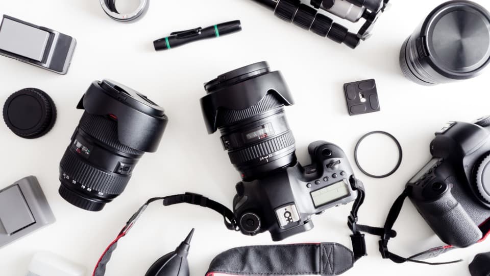Eine strukturierte Übersicht von Fotoausrüstung mit Spiegelreflexkameras, Objektiven und Zubehör vor dem sicheren Verpacken für den Umzug mit DACHSER & KOLB.