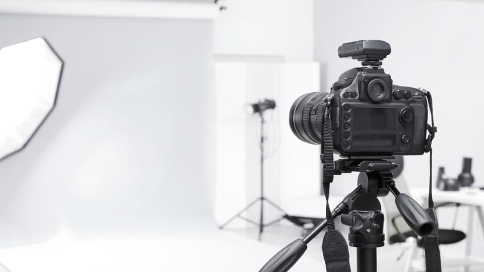 Eine Kamera auf einem Stativ im Vordergrund eines Fotostudios zur Veranschaulichung der Transport-Entscheidung bei DACHSER & KOLB.