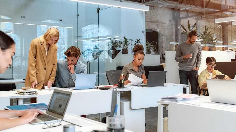 Employees working flexibly on laptops in a modern co-working space.