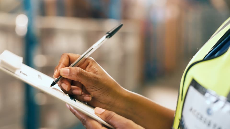 A logistics employee documents the current status on a clipboard in the warehouse for the expat move.