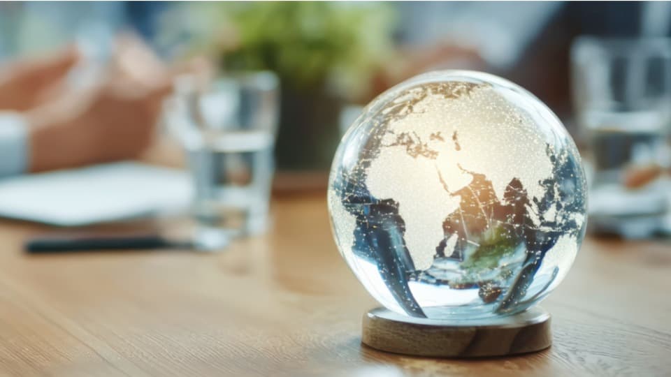 An illuminated glass globe on a conference table symbolizes DACHSER & KOLB’s global network for worldwide home search and relocation of expats.