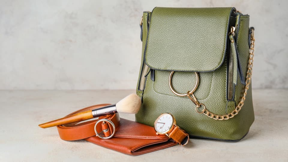 Eine hochwertige grüne Handtasche und persönliche Accessoires, sorgfältig vorbereitet für den geschützten Premium-Umzug mit DACHSER & KOLB.