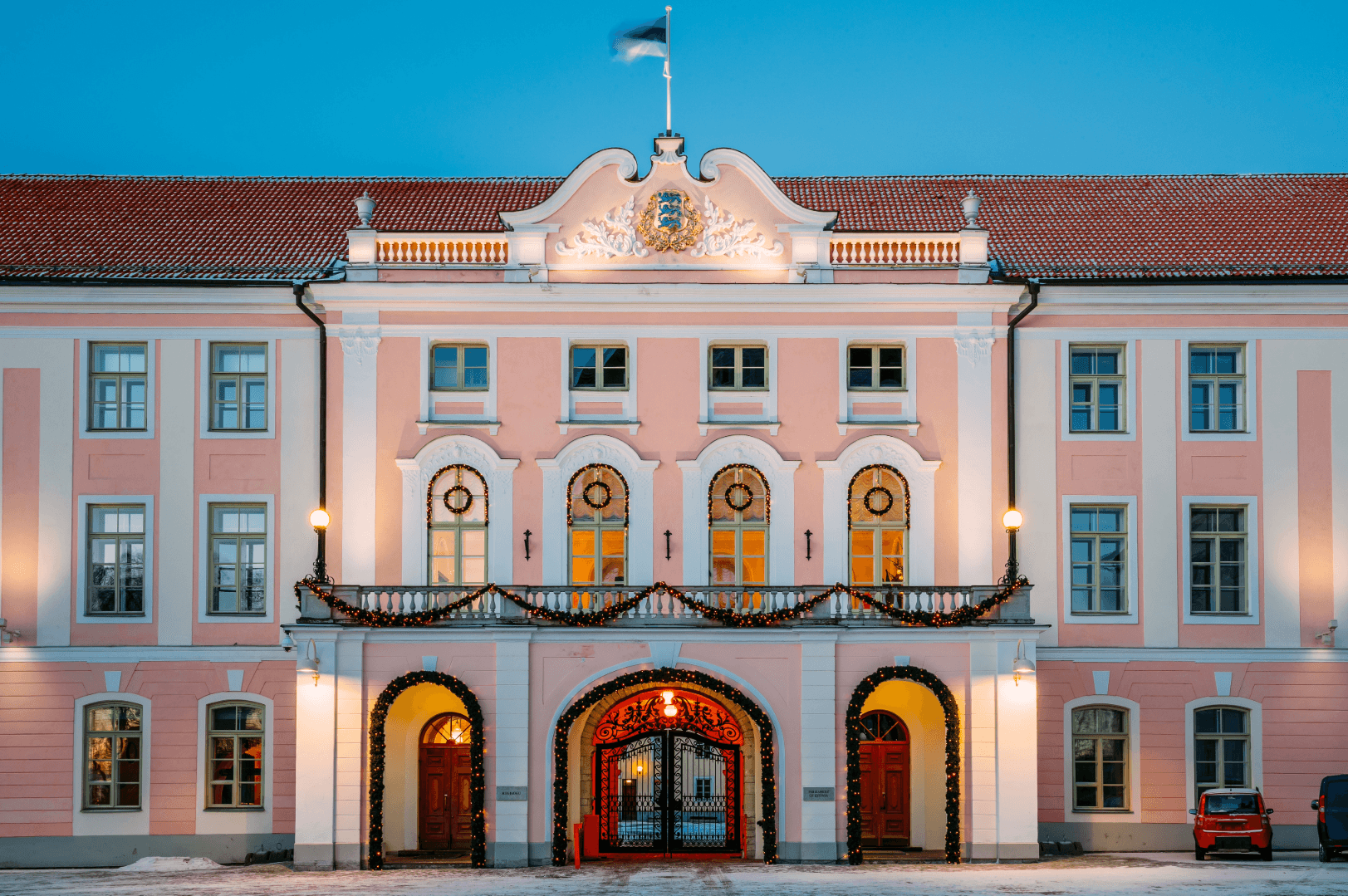 Historisches Gebäude in Estland mit Estlandflagge, rosa Fassade und beleuchtetem Eingang
