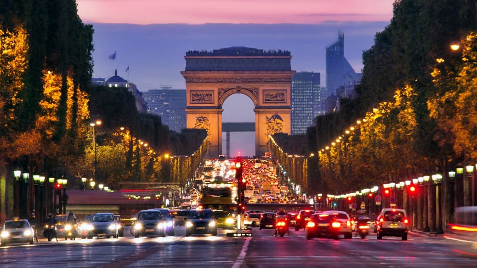 Arc de Triomphe in Paris bei Abenddämmerung mit Verkehr auf den Champs-Élysées