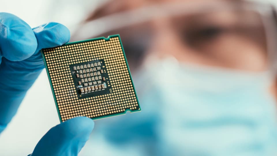 A person holds up a semiconductor to the camera to symbolize the semiconductor industry's special significance in Taiwan