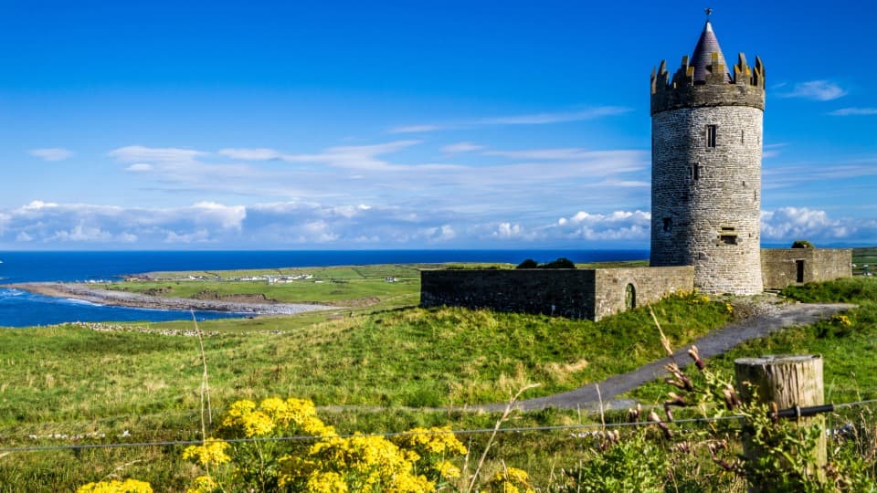 Das historische Doonagore Castle an der irischen Westküste als Symbol für die grüne Landschaft und Natur in Irland.