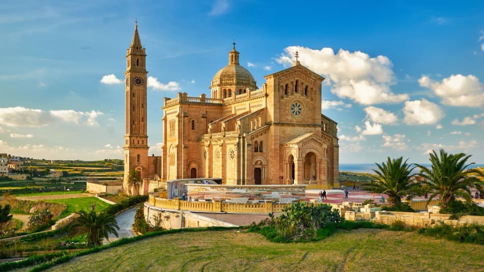Die majestätische Basilika Ta' Pinu auf Gozo, umgeben von grüner Landschaft unter blauem Himmel – ein Wahrzeichen maltesischer Kultur und Glaube.