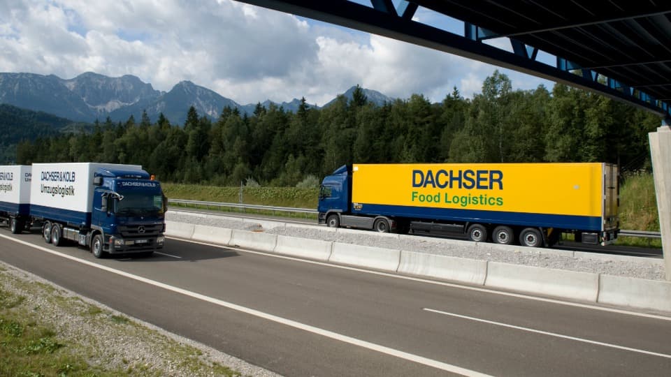 A DACHSER & KOLB moving truck and a DACHSER Food Logistics truck on the highway in front of a mountain backdrop, illustrating the strength of the network.