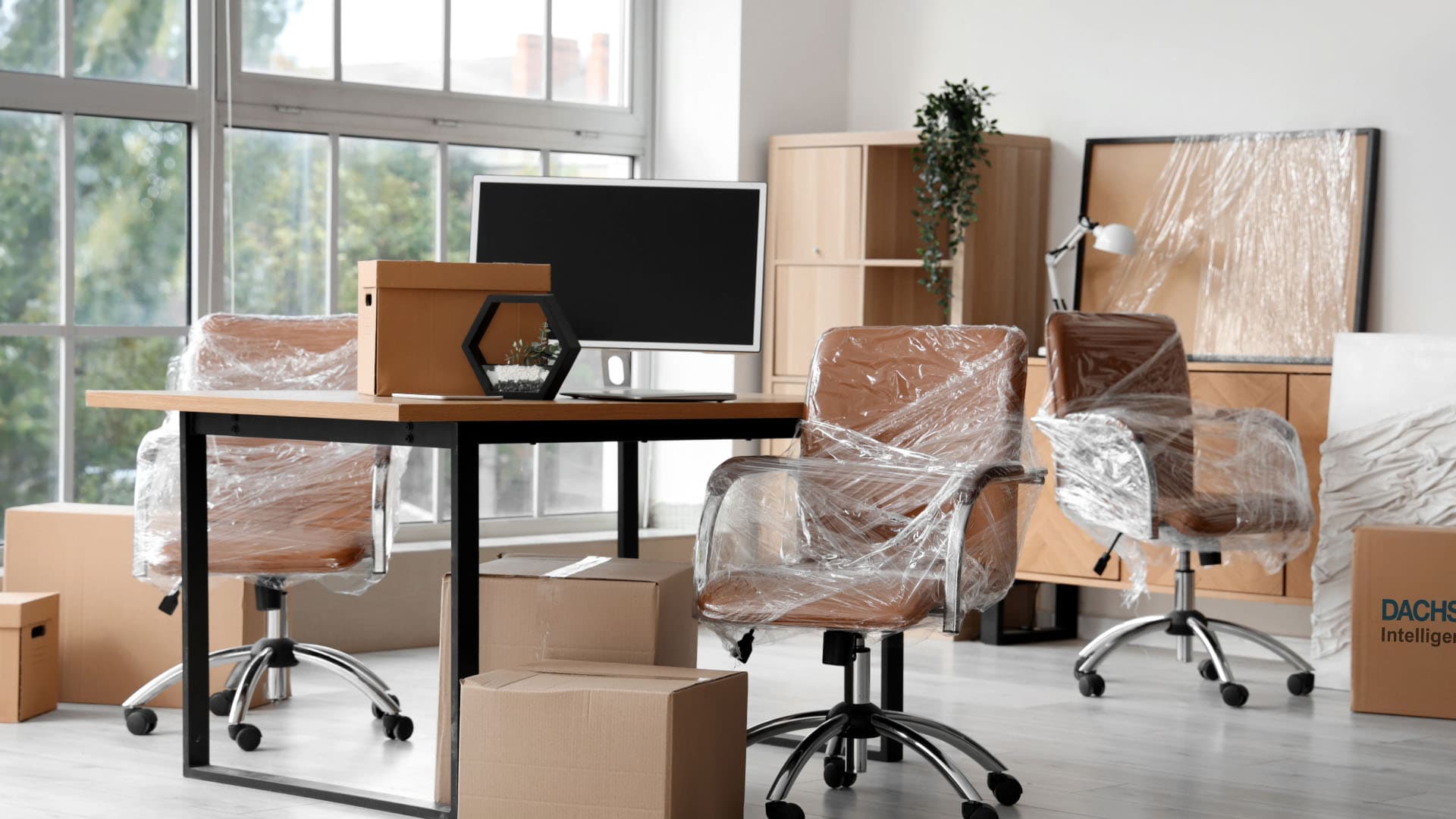 Wrapped office chairs, desk and boxes in a bright office during a move