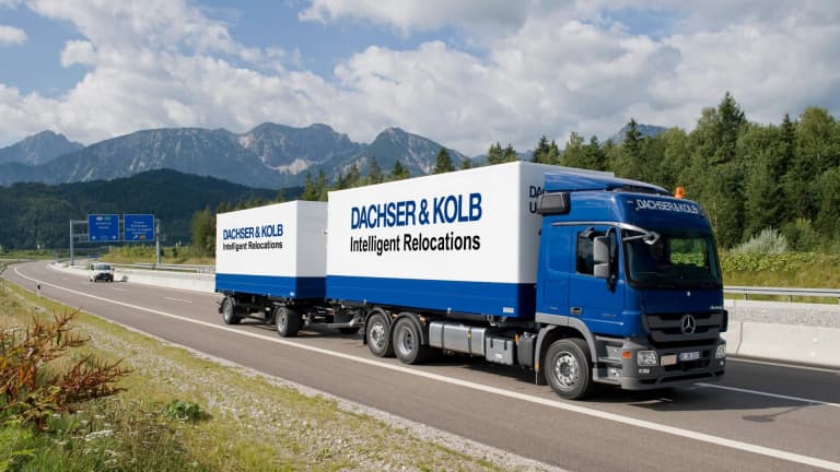 A blue DACHSER & KOLB truck trailer is traveling on a highway outside Bergen, symbolizing the strong logistics network for professional corporate relocations.