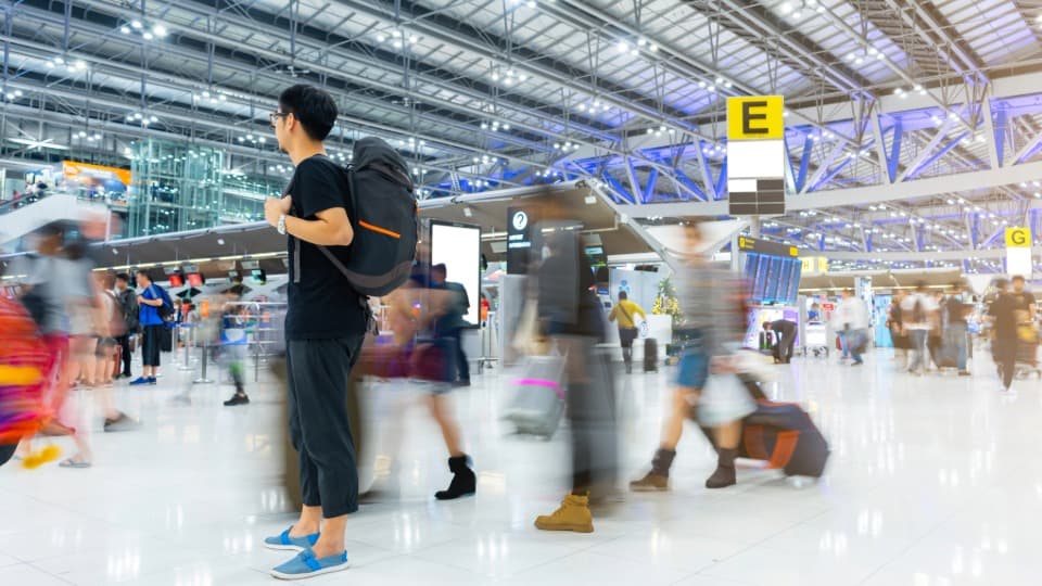 Traveler with backpack at busy airport before departure to Thailand