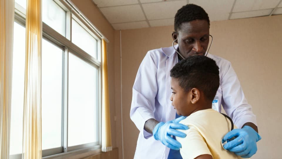 A doctor from Tanzania examines a child with a stethoscope
