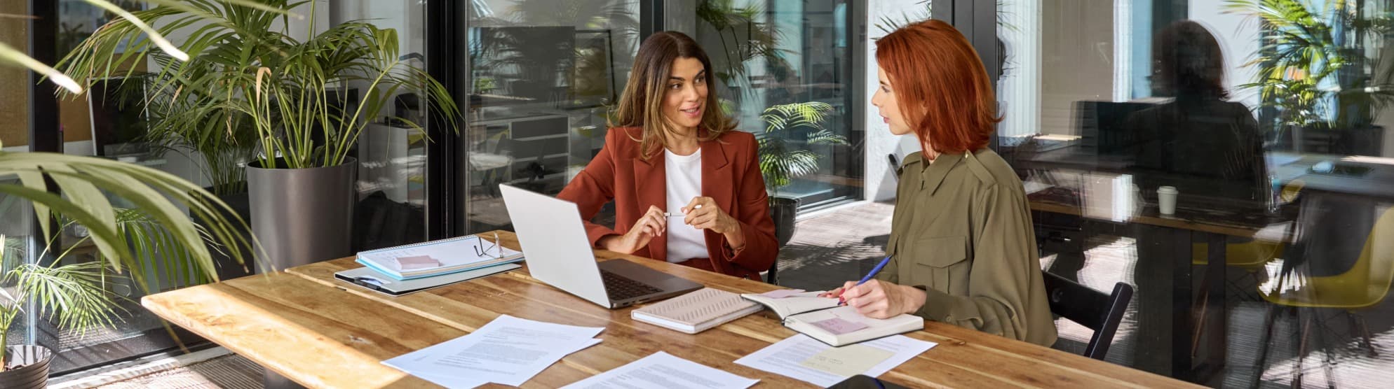 Global mobility consulting at DACHSER & KOLB – Two women discuss the planning of an employee assignment on a laptop in a modern office.