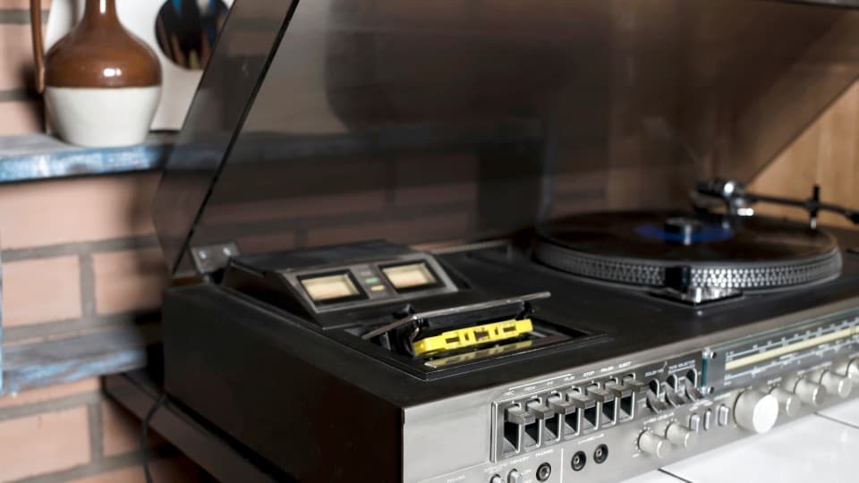 Ein klassischer HiFi-Plattenspieler mit geöffneter Staubschutzhaube und Tonarm auf einer Musikanlage vor dem sicheren Umzug mit DACHSER & KOLB.