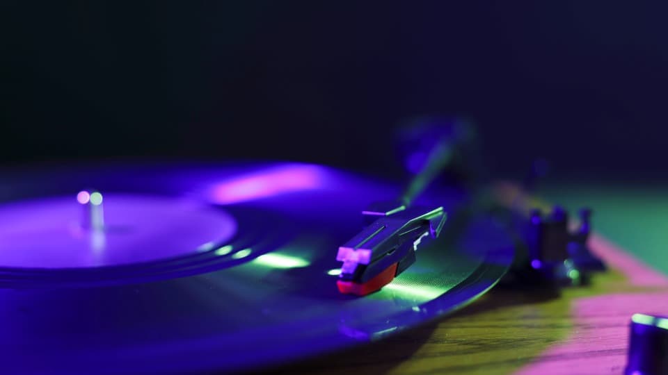 Eine detaillierte Nahaufnahme einer Plattenspielernadel auf einer Vinyl-Schallplatte vor der Transportsicherung für den Umzug mit DACHSER & KOLB.
