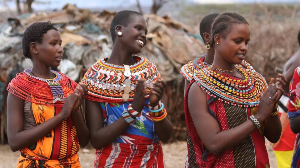 Culture in Kenya: Several Kenyans in traditional dress clap their hands