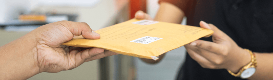 Two people exchanging a large envelope – symbolic image for mail forwarding via Nachsendeauftrag service.
