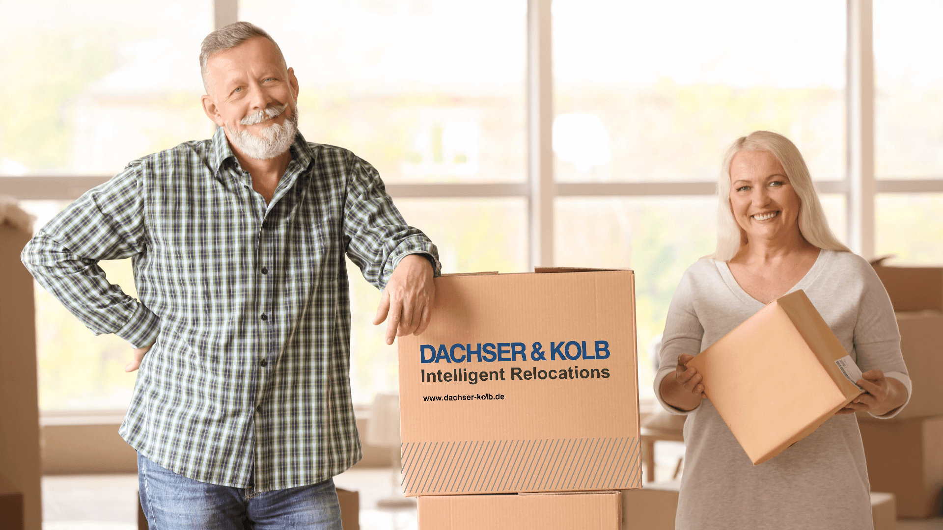 Senior couple moving to upscale residence with DACHSER & KOLB – bright room with moving boxes