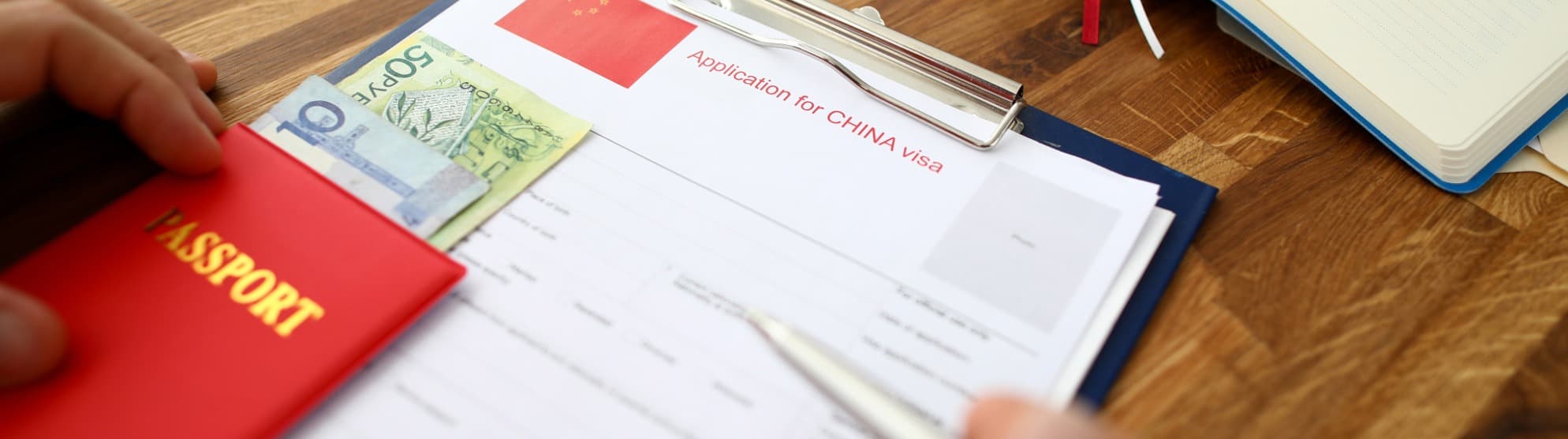 Reisepass, Geldscheine und Visumantrag für China auf einem Schreibtisch