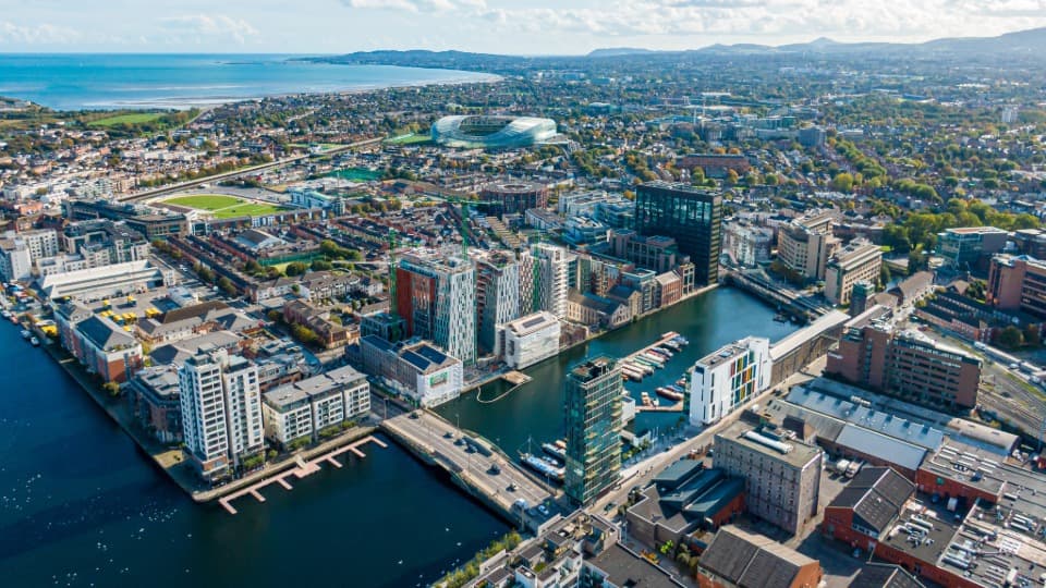 Drohnenaufnahme des Grand Canal Dock in Dublin mit dem Aviva Stadium im Hintergrund als Zentrum für Irlands Tech-Branche.