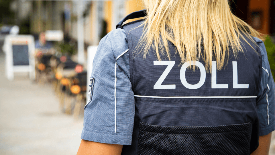 Zollbeamtin von hinten in Uniform in einer Fußgängerzone – Symbolbild für Zoll und Grenzkontrolle.