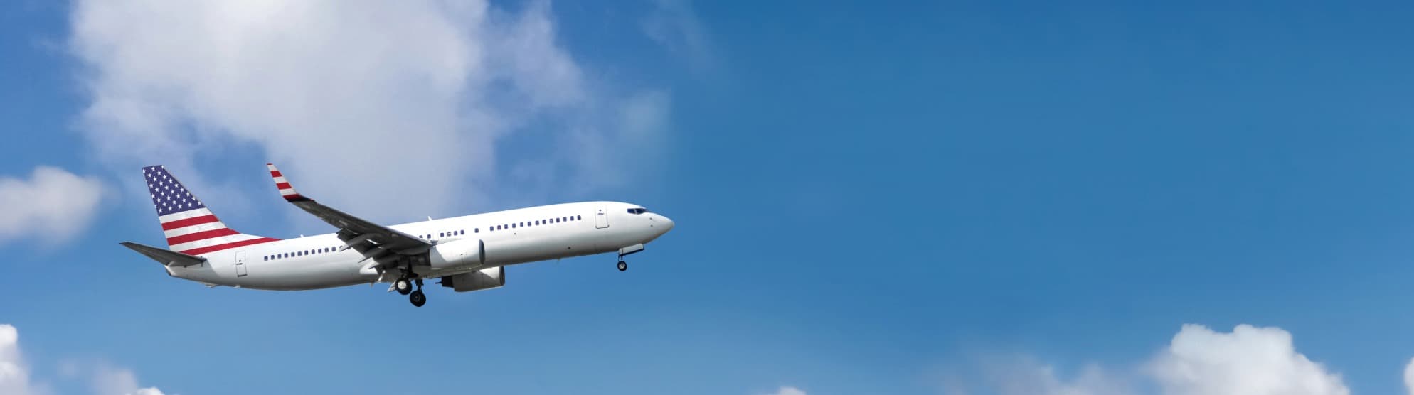 Airplane with U.S. flag tail approaching – symbolizing customs regulations and import requirements for moving to the USA.