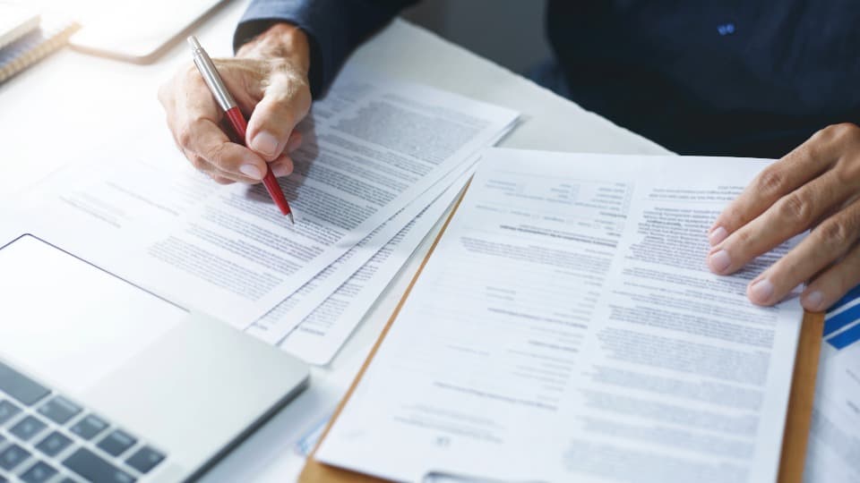 Person reviews and marks customs forms at a desk, symbol for customs Thailand to Germany.
