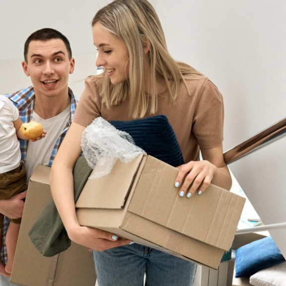 A happy family excitedly carrying moving boxes into their new home during an international relocation with DACHSER & KOLB.