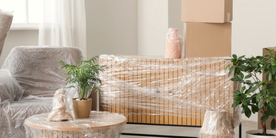 Ein Wohnraum mit verpackten Möbeln und gestapelten Umzugskartons. Symbolisiert den Relocation Service für Privatpersonen.