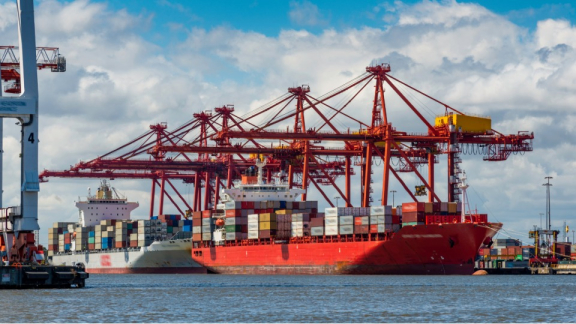 Red container cranes at the Port of Melbourne unloading ocean freight for customs clearance during a relocation to Australia with DACHSER & KOLB.
