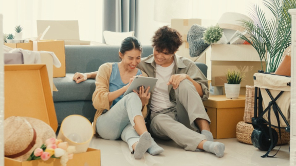 A happy couple using a tablet to calculate relocation costs for New Zealand with the online moving calculator from DACHSER & KOLB.
