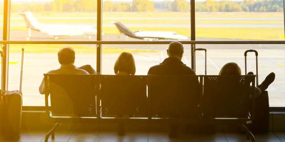 Reisende mit Koffern am Flughafen warten auf ihren Flug – Symbolbild für internationalen Relocation Service