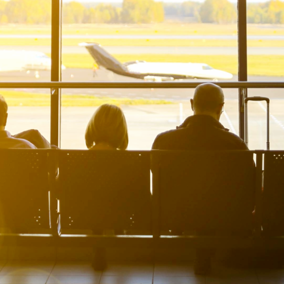 Reisende mit Koffern am Flughafen warten auf ihren Flug – Symbolbild für internationalen Relocation Service