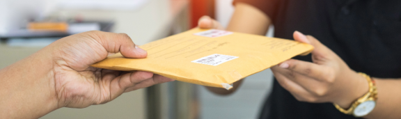 Zwei Personen übergeben sich einen Briefumschlag – Symbolbild für Nachsendeauftrag und Weiterleitung von Post.