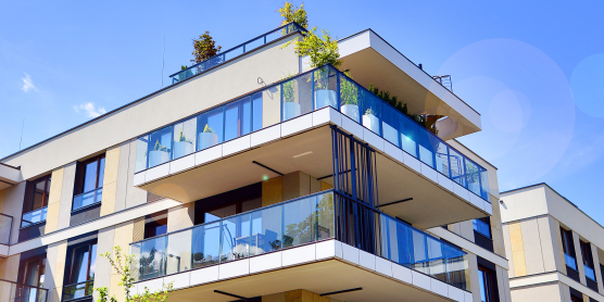 Modernes Mehrfamilienhaus in Deutschland mit Balkonen unter blauem Himmel, relevant für den Mietspiegel.