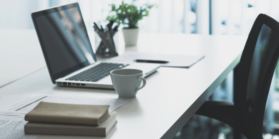 Heller Home Office Arbeitsplatz nach Umzug mit Laptop, Kaffeetasse, Büchern und Stuhl. Einrichtungsideen für modernes Arbeiten zu Hause.