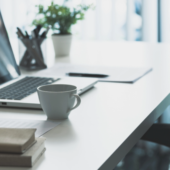 Heller Home Office Arbeitsplatz nach Umzug mit Laptop, Kaffeetasse, Büchern und Stuhl. Einrichtungsideen für modernes Arbeiten zu Hause.