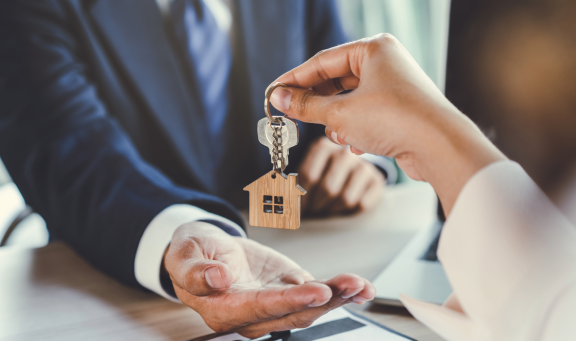 Schlüsselübergabe mit Hausanhänger – symbolisiert Schutz und Versicherungsoptionen rund um den Wohnungsumzug.