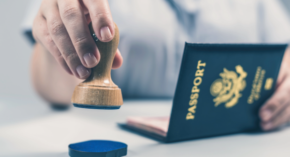 Ein Reisepass wird gestempelt. Symbolisiert die Formalitäten und Einreise-Organisation beim Relocation Service für Privatpersonen.
