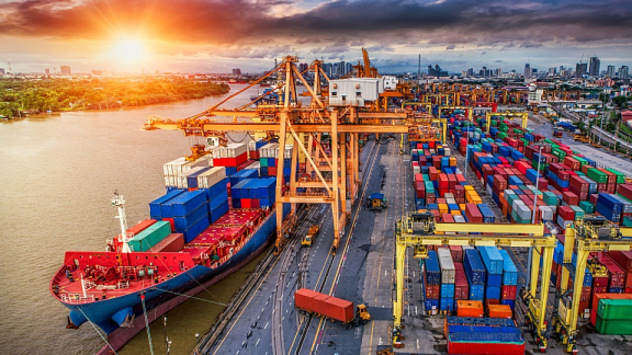 Containerschiff wird im Hafen von Bangkok am Fluss Chao Phraya beladen für den Container-Umzug nach Thailand mit DACHSER & KOLB.